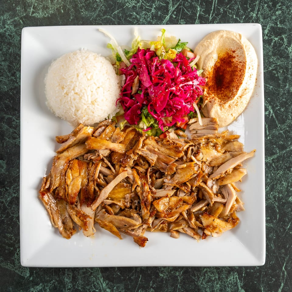 Istanbul Kitchen's chicken shawarma plate with rice, red cabbage salad, and hummus on a white plate.